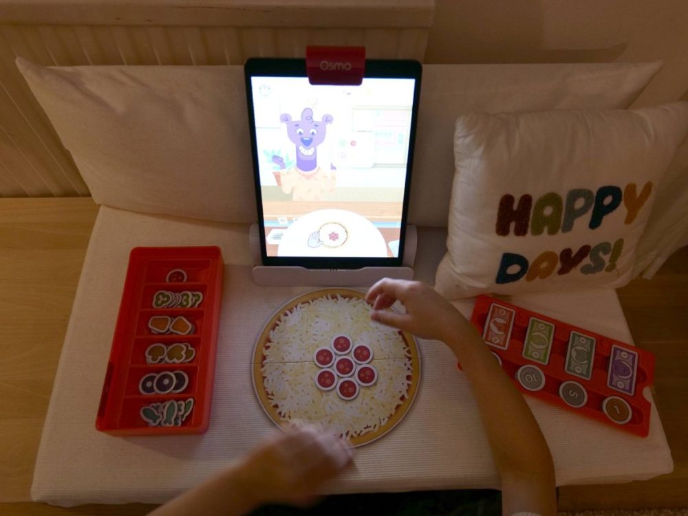 Osmo Pizza Co. innehåller ingredienser, pengar, en ställning och spegel för iPad samt en pizza.